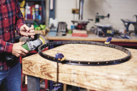 man using angle grinder to cut in to a bicycle rim clamped on to a&hellip;